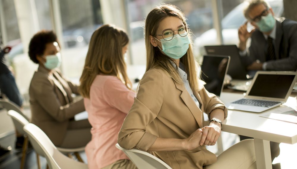 Pretty young woman and group business people have a meeting and working in the office and wear mask as protection from corona virus