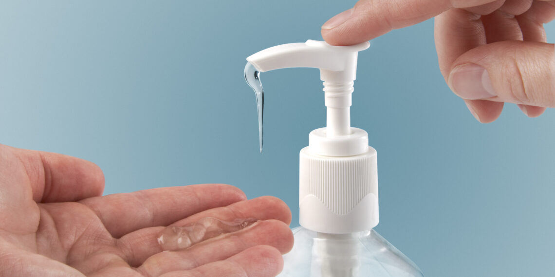 Pumping hand sanitizer into hand.