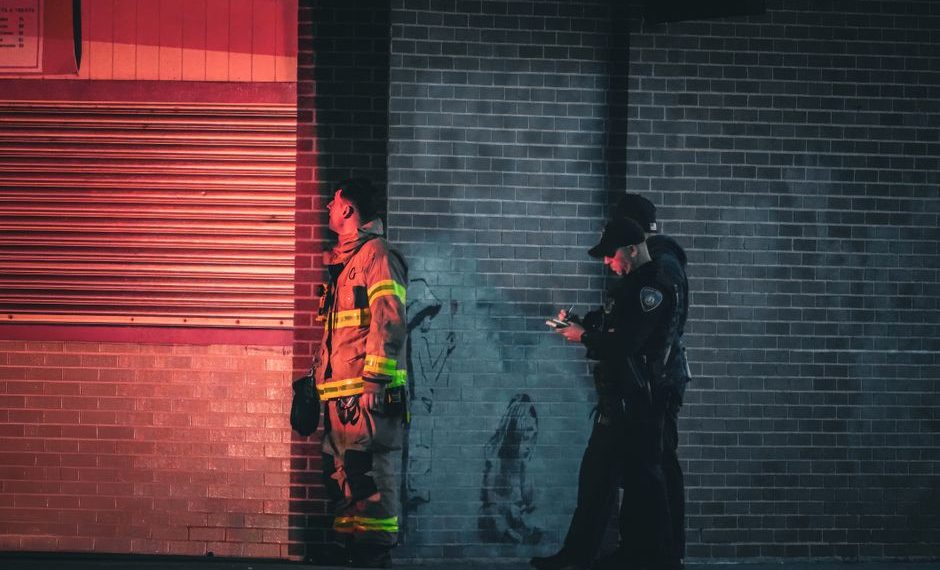 Firefighter in safety gear conducting fire watch patrol with flashlight and clipboard at construction site