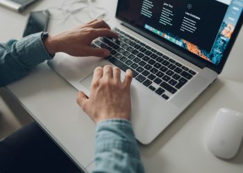 Person working on a laptop while editing written content