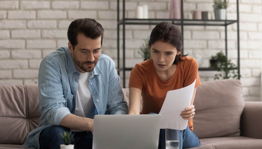 Person reviewing loan documents with calculator and laptop, comparing same-day lending options and interest rates