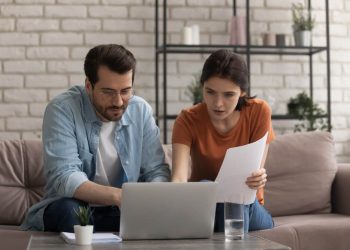 Person reviewing loan documents with calculator and laptop, comparing same-day lending options and interest rates
